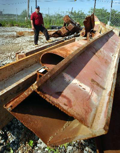 Figure 43. (09/05) WTC Perimeter column panels with their spandrel belts folded about a vertical axis. Steel column showing tight uniform curl with differential strain through thickness, inconsistent with thermal warping.
  <br>
  - Image by NIST.